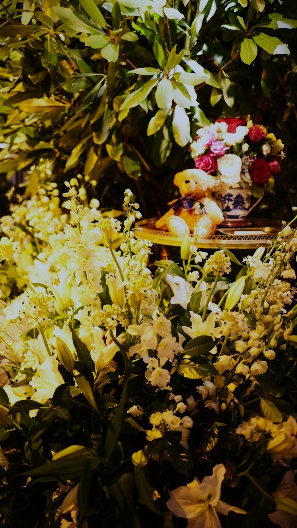 Green installation in warm lamplight with a small bear